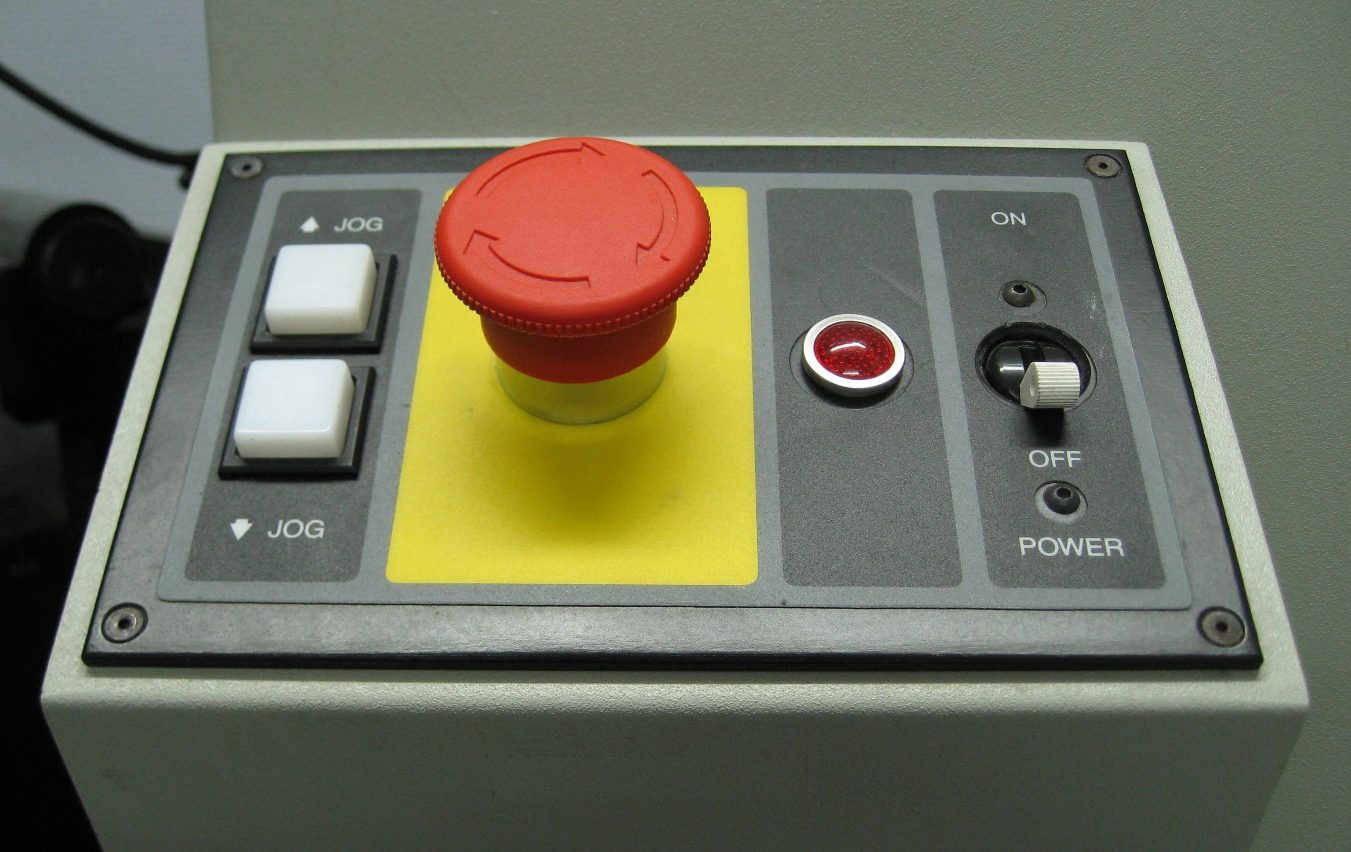 A red emergency stop button, the kind of physical kill switch used on industrial machinery.